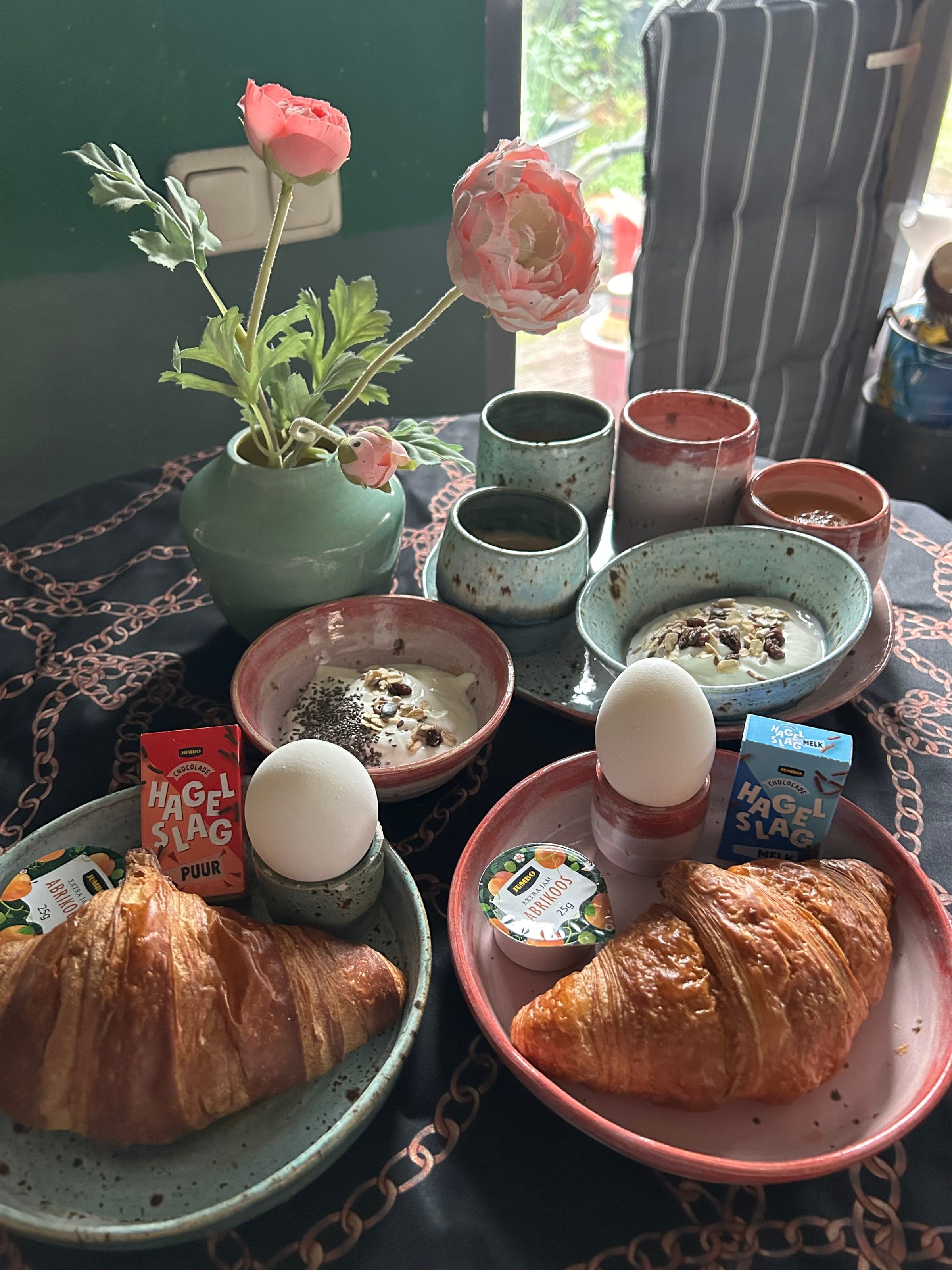 Gedekte ontbijttafel met het zelfgemaakte servies en verse croissants