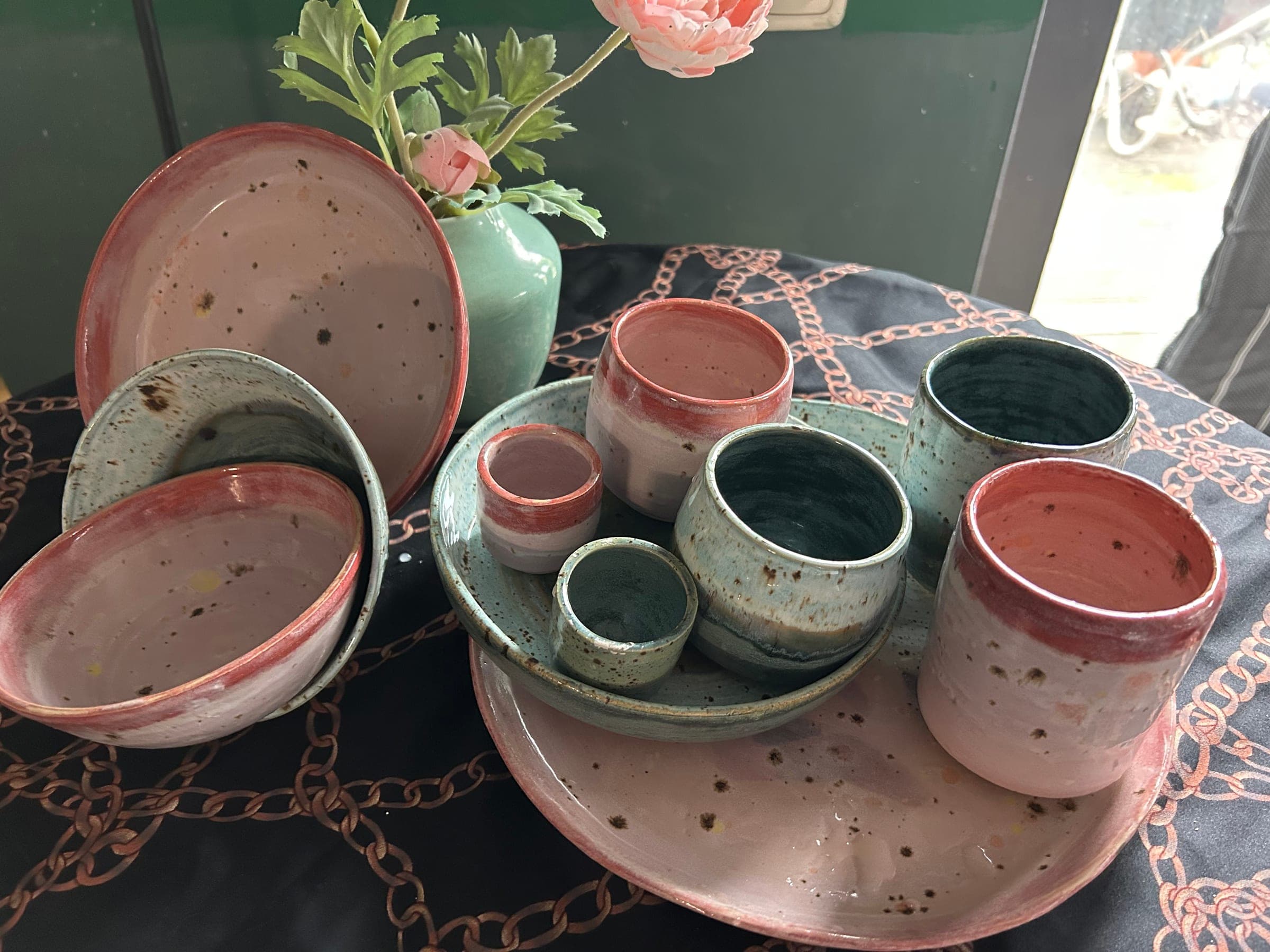 Detail van de geglazuurde bekers, kommen en borden in roze en groen